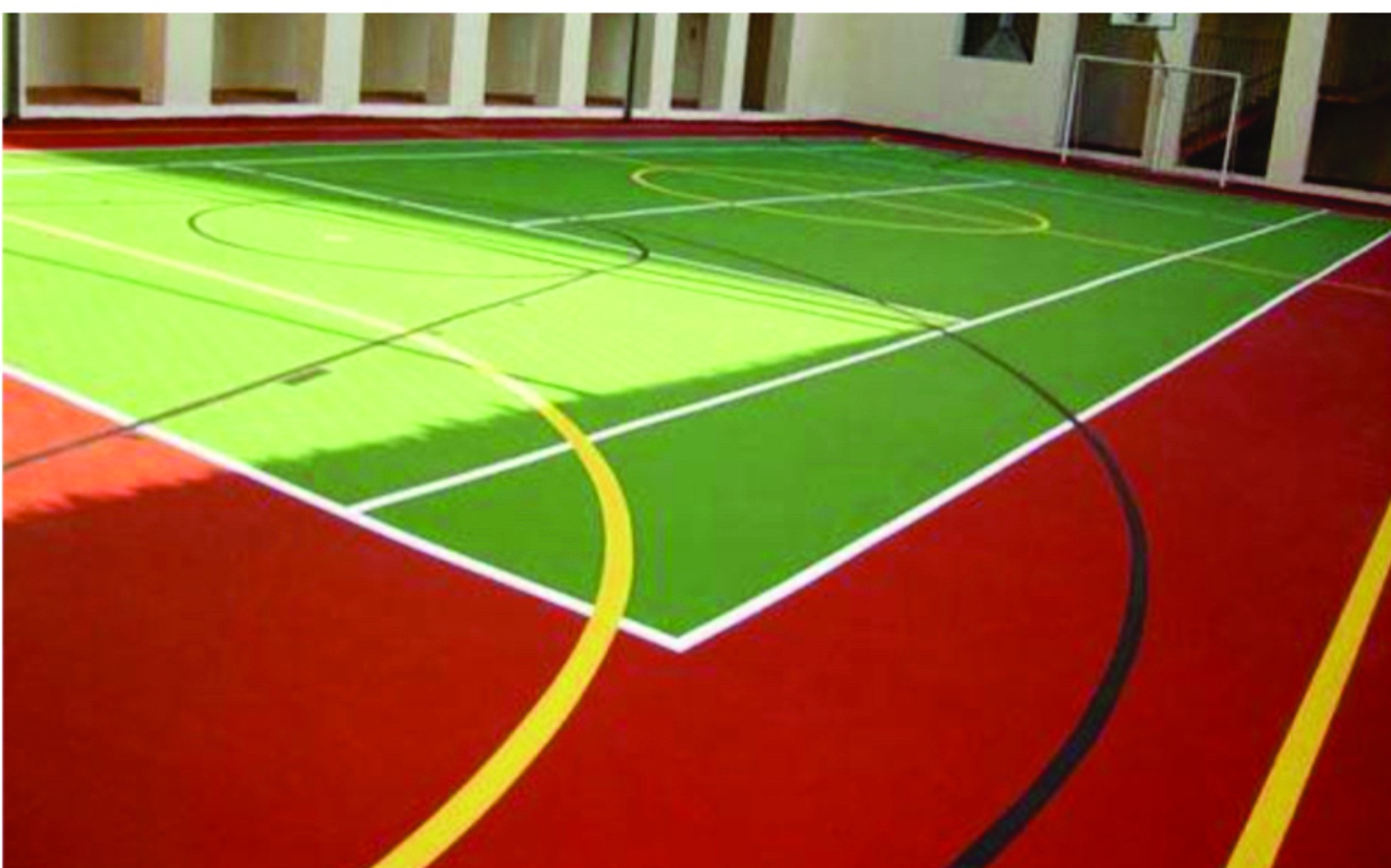 Quadra poliesportiva pintada em verde, vermelho e amarelo